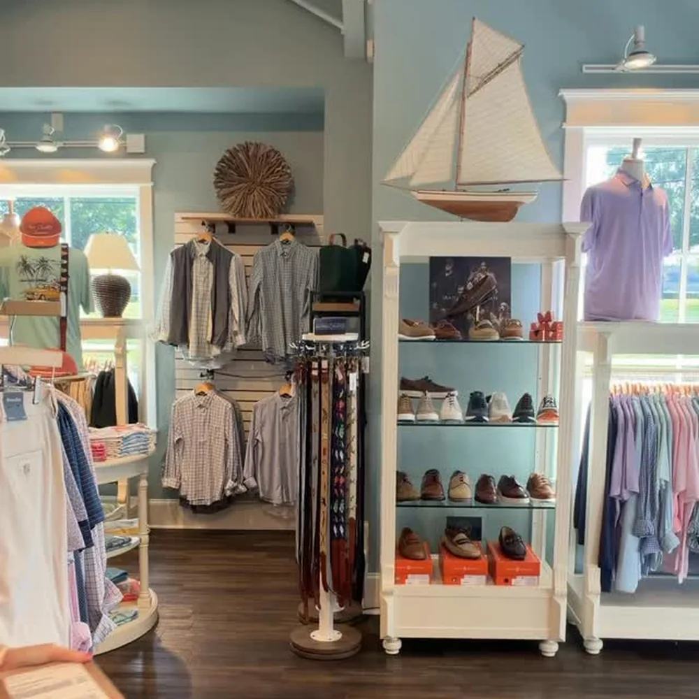 Low Country Clothier sales floor with a new shipment box, shoes on a white display shelf and racks of shirts and sweaters